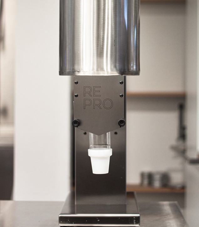 Close-up of a stainless steel ice cream dispenser filling ice cream into a goblet